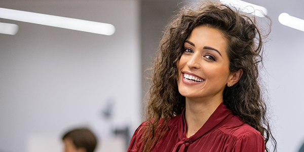 businesswoman standing in creative office and looking at camera while smiling.
