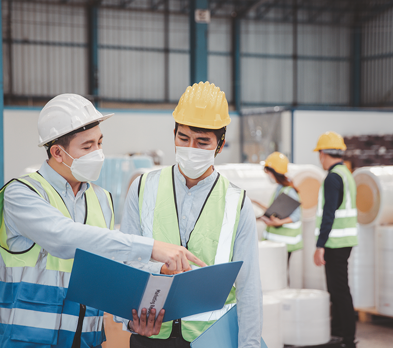 Factory manager and engineer in medical mask and safety protective suite using computer laptop and digital tablet working discuss together